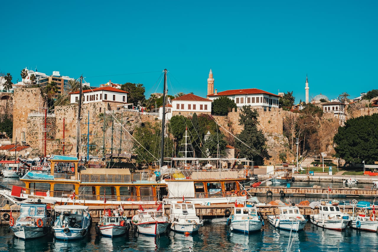 Antalya's ancient harbour with boats moored alongside Roman-era stone walls — the beautiful Mediterranean setting UK patients discover when travelling for dental treatment