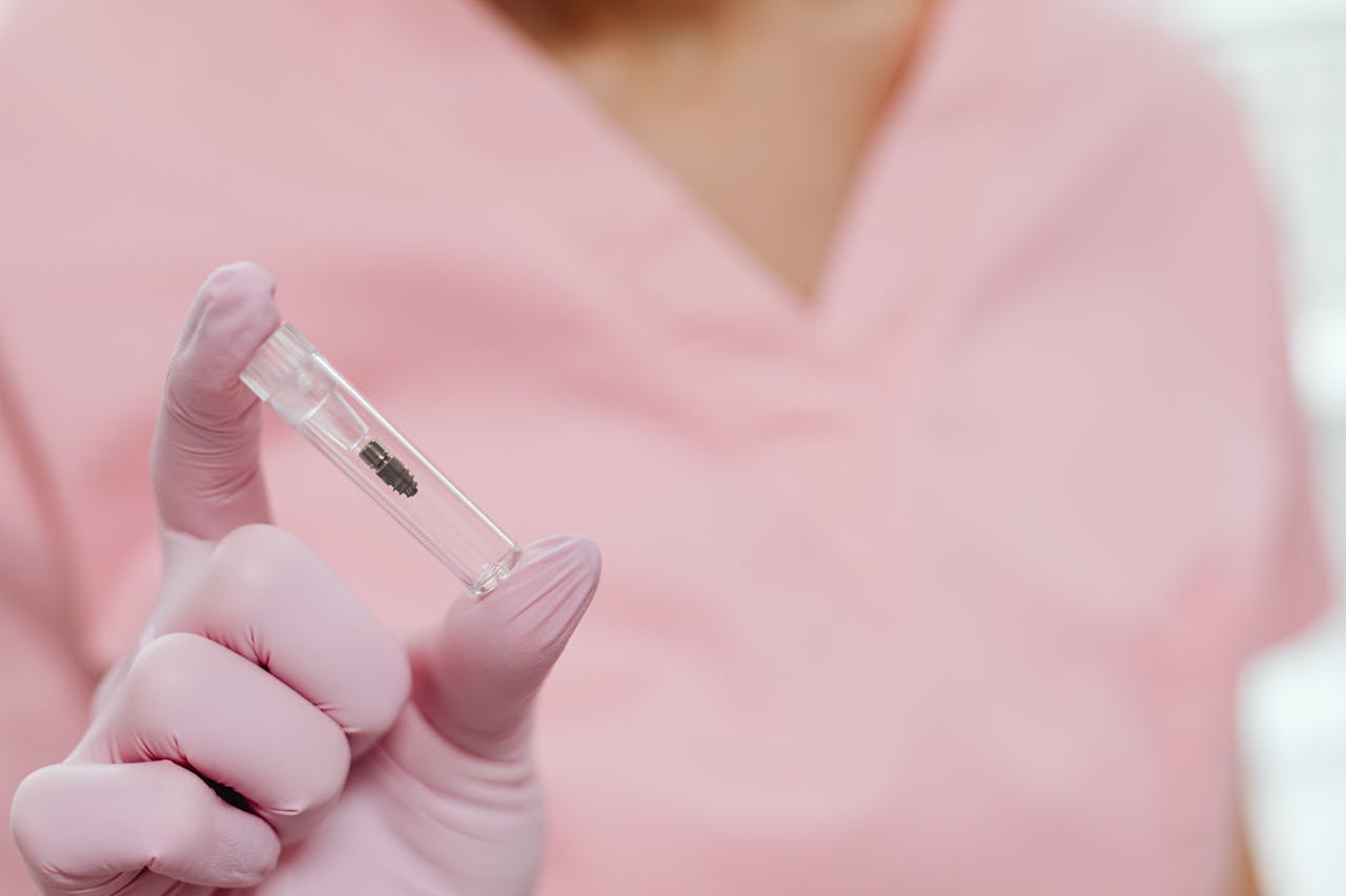 Dental professional holding a titanium implant post — the Straumann and Nobel Biocare systems used by top Turkish implant specialists in Antalya